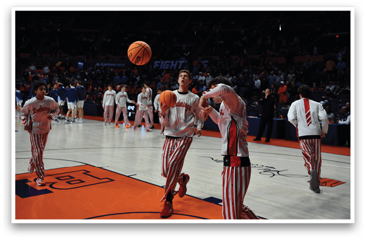 A basketball game is in progress with a group of men playing. One of the players is attempting to shoot the ball through the hoop. The crowd is watching the game intently. AI generated content
