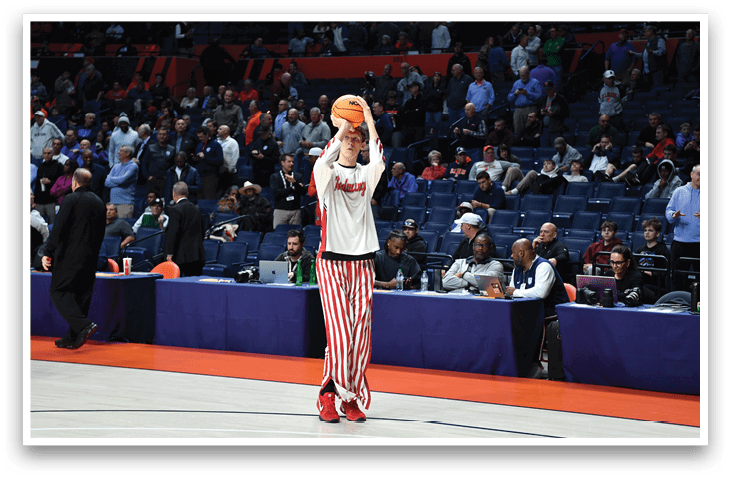 A man in a white shirt and red and white striped pants is holding a basketball. AI generated content