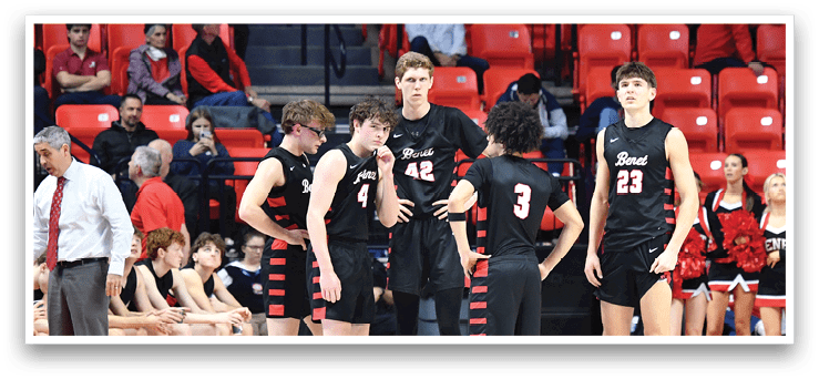 A group of men are standing on a basketball court, with some of them wearing black and red uniforms. They are surrounded by a crowd of people, some of whom are sitting on chairs. The men are engaged in a game of basketball, with one of them holding a basketball in his hand. AI generated content