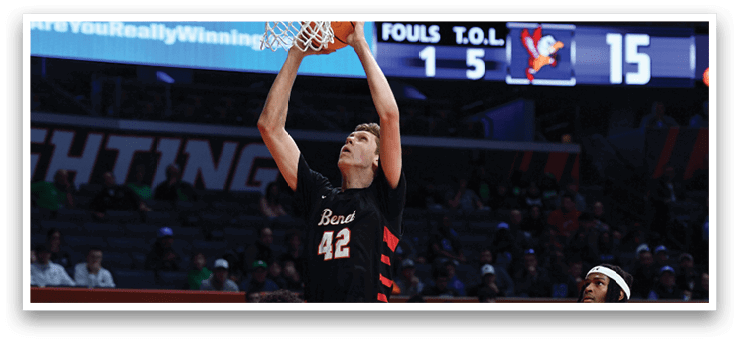 A basketball player is jumping to dunk the ball, while other players watch from the sidelines. AI generated content