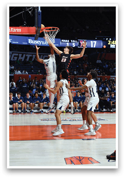 A basketball game is in progress with a player attempting to dunk the ball. The crowd is watching intently as the player jumps in the air. AI generated content