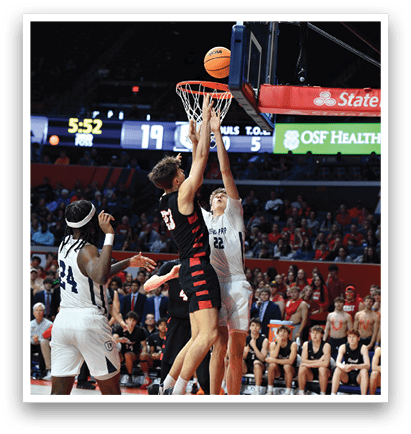 A basketball game is in progress with two teams playing. One player is attempting to score a basket by jumping over another player. The crowd is watching intently as the players compete. AI generated content