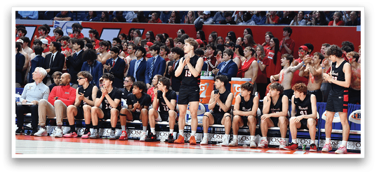 A group of young men are sitting on a bench, wearing black and red uniforms. They are watching a game, with some of them holding their hands up in the air. The crowd is cheering them on, creating an exciting atmosphere. AI generated content
