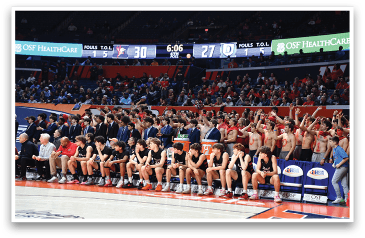 A group of men are sitting on the floor of a basketball court, watching a game. AI generated content