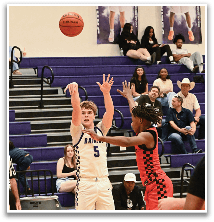 A basketball game is taking place with a player in the air attempting to shoot the ball. The crowd is watching intently as the players compete. Contenido generado con IA