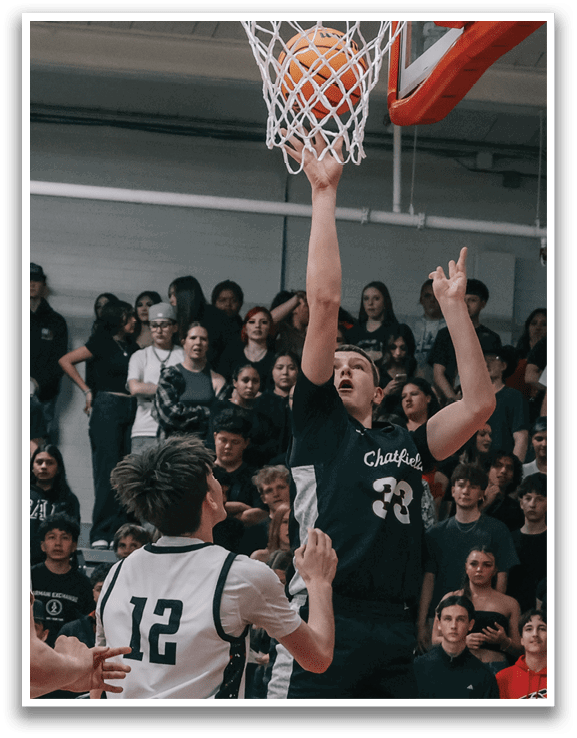A basketball game is in progress with a player in the air attempting to score a basket. The crowd is watching intently as the player jumps to make the shot. AI generated content