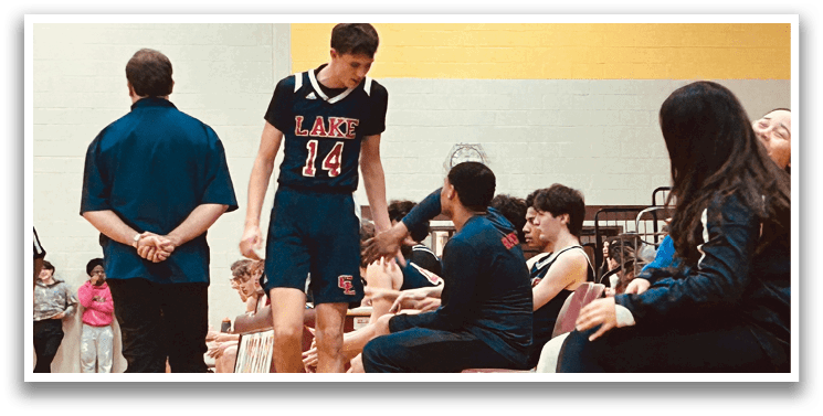 A group of people are sitting on chairs, watching a basketball game. A man in a basketball uniform is walking by, possibly taking a break or preparing to play. AI generated content