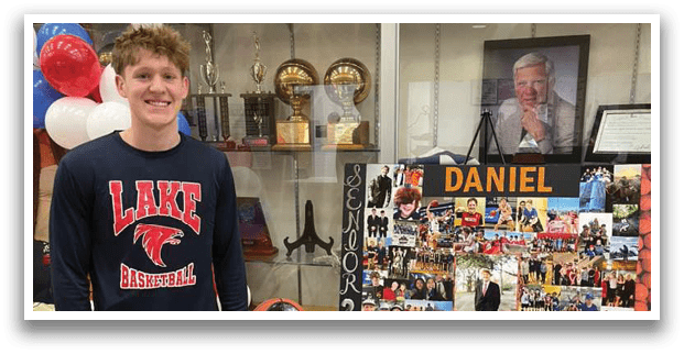 A young man in a blue shirt stands in front of a display of photos and trophies. AI generated content