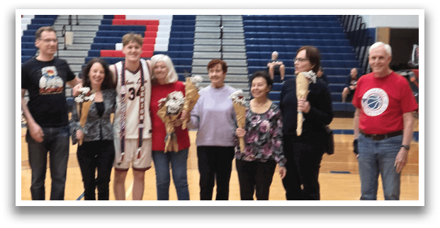 A group of people, including a man in a basketball uniform, pose for a photo on a basketball court. AI generated content