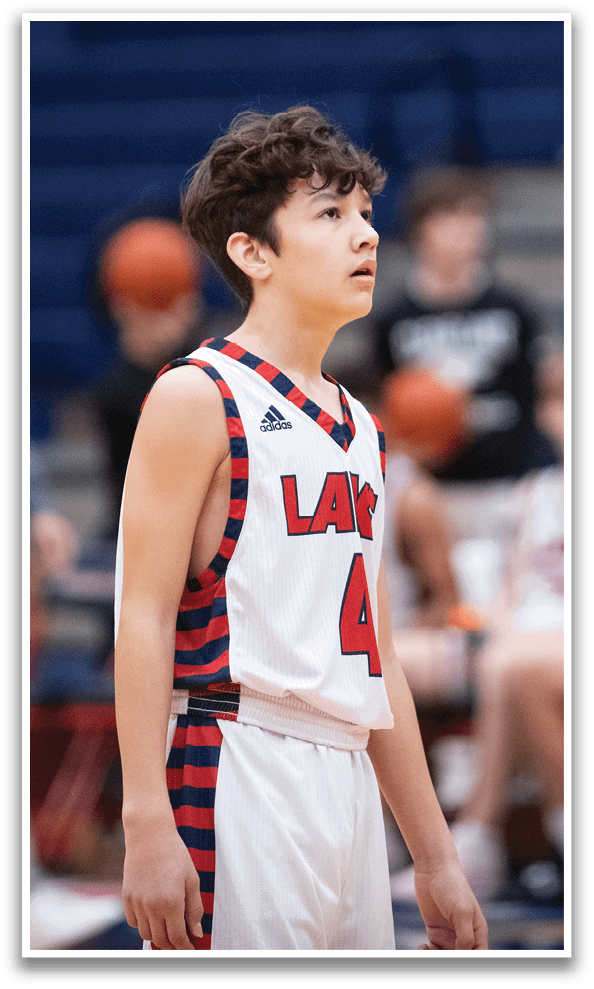 A young boy wearing a basketball uniform stands on a basketball court. AI generated content