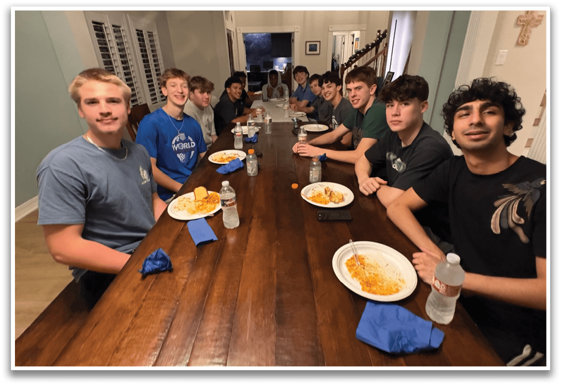 A group of teenagers are sitting around a wooden dining table, enjoying a meal together. AI generated content