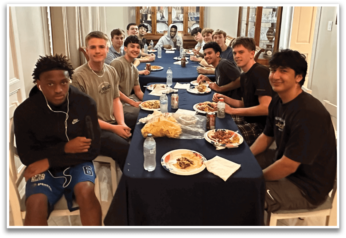 A group of young men are sitting around a table, eating and drinking. There are several bottles, cups, and bowls on the table, as well as a few chairs. The men are engaged in conversation and enjoying their meal together. AI generated content