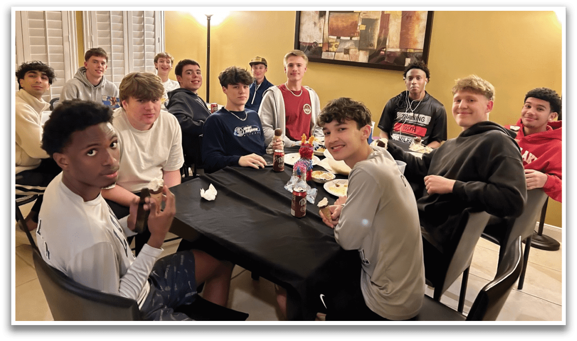 A group of people are sitting around a table, eating and drinking. They are all wearing shirts and are engaged in conversation. AI generated content