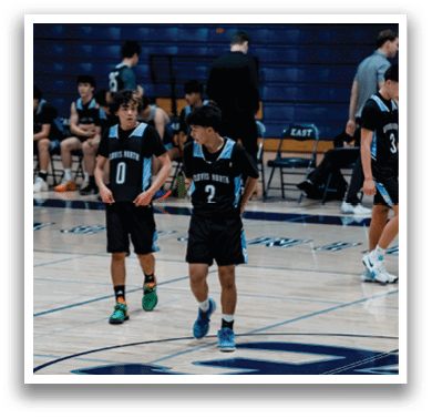 Two boys wearing black shirts and shorts are walking on a basketball court. AI generated content
