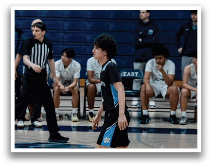A boy in a black and blue uniform walks on a basketball court. AI generated content
