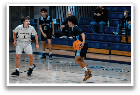 A boy in a black shirt and blue shorts is holding a basketball while playing in a gym. AI generated content