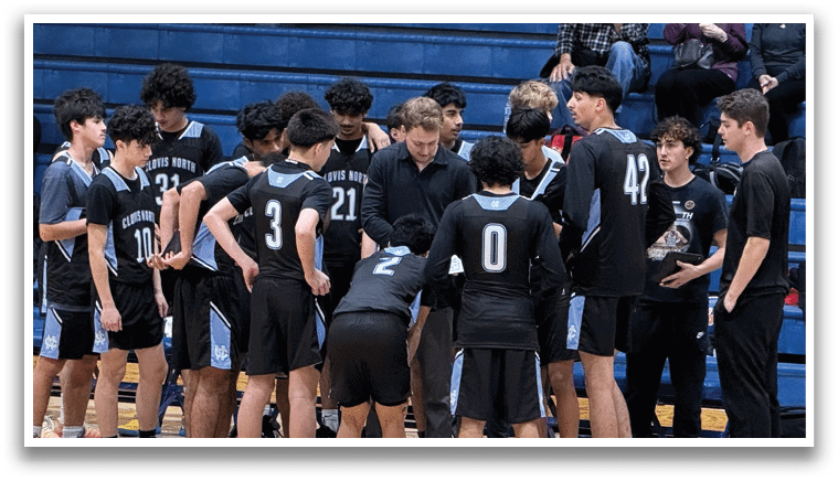 A group of young men wearing black shirts and shorts are standing on a basketball court. They are huddled together, possibly discussing their game strategy or sharing encouragement. The players are positioned around the court, with some standing closer to the foreground and others further back. The scene suggests a sense of camaraderie and teamwork among the players. AI generated content