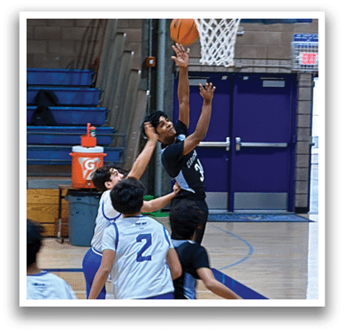 A group of young men playing basketball on a court. One player is attempting to block a shot. AI generated content