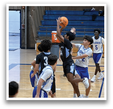 A group of young men playing basketball on a court. One player is attempting to block a shot. AI generated content