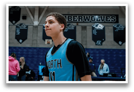 A young man wearing a blue and black basketball jersey stands in front of a crowd of people. AI generated content