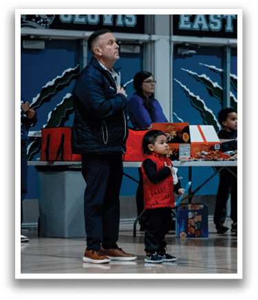 A man and a young boy stand in front of a table with snacks. AI generated content