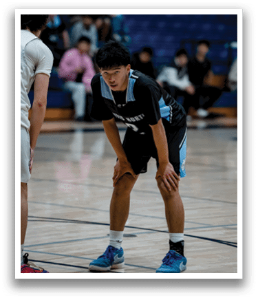 A basketball player wearing a black shirt and shorts is crouching on the court. AI generated content