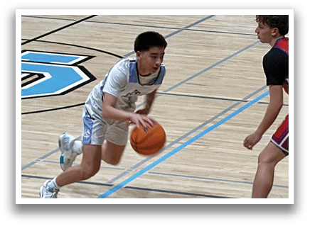 Two boys playing basketball on a court. One boy is holding a basketball and the other is running towards him. AI generated content
