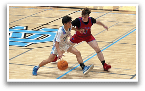 Two young men are playing basketball on a court. One player is holding a basketball while the other tries to block him. AI generated content