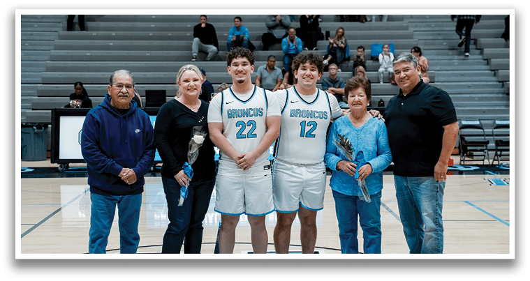 A group of people, including two men in uniform, pose for a photo on a basketball court. AI generated content