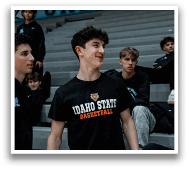A group of young men are sitting on bleachers, watching a basketball game. One of the players is wearing a black shirt with the words “Idaho State Basketball" on it. AI generated content