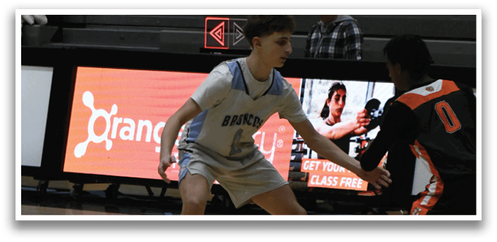 A basketball player is running on the court while another player tries to block him. AI generated content