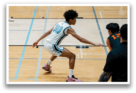 Two basketball players are on the court, one wearing a white jersey and the other wearing an orange jersey. The player in the white jersey is running towards the ball, while the player in the orange jersey is trying to block him. AI generated content