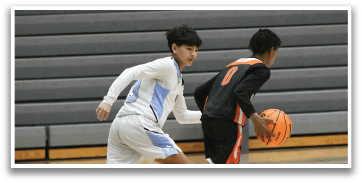 Two boys playing basketball on a court. One boy is holding a basketball and the other is running towards him. AI generated content