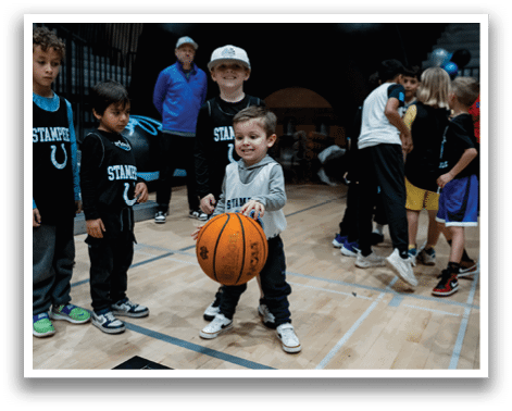 A young boy is holding a basketball while standing in front of a group of children. AI generated content