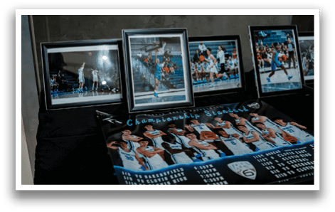 A table with four framed photos of basketball players and a poster advertising the team. AI generated content