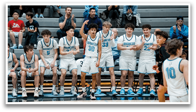 A group of young men are sitting on a bench, watching a basketball game. AI generated content