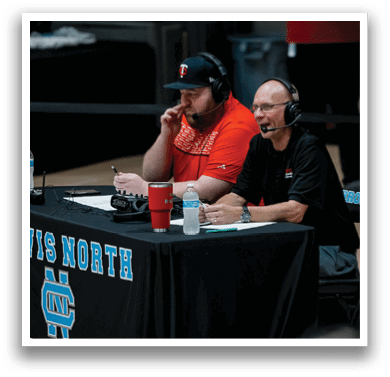 Two men are sitting at a table with a microphone, possibly discussing a sports event. AI generated content