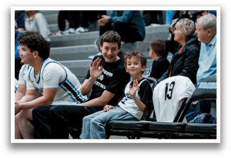 A young boy sits on a bench next to a group of men, including a boy in a white shirt. AI generated content