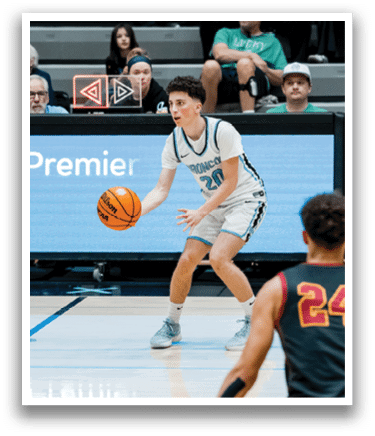 A basketball game is taking place with a group of men playing. One man is holding a basketball and appears to be preparing to shoot it. The game is being watched by a crowd of people who are seated on chairs. AI generated content