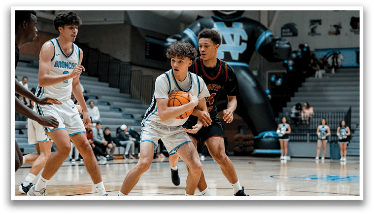 A group of young men playing basketball on a court. One player is holding a basketball and another player is trying to block him. AI generated content