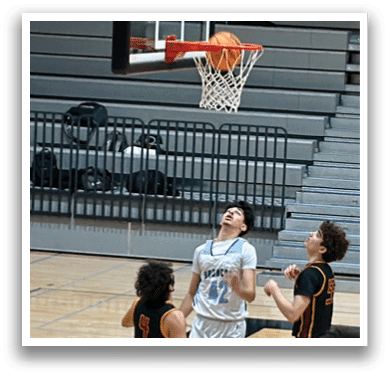A group of young men playing basketball on a court. One player is attempting to block a shot. AI generated content