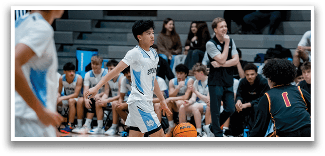 A group of people are playing basketball on a court. There are several players on the court, with one player holding a basketball. The players are wearing uniforms and are actively engaged in the game. The audience is watching the game from the bleachers, with some players sitting and others standing. The scene is lively and full of energy as the players compete against each other. AI generated content