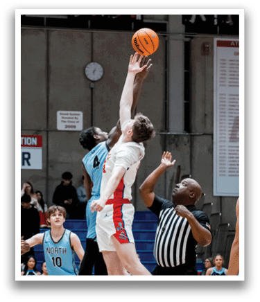 A basketball game is in progress with a player jumping to block a shot. AI generated content