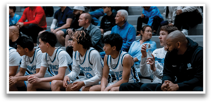 A group of young men are sitting on a bench, some of them wearing basketball uniforms. They are waiting for their turn to play. AI generated content