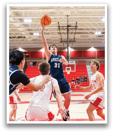 A basketball game is in progress with players on the court. A man is jumping to shoot the ball, while other players are trying to defend. The scene takes place in a gymnasium with a basketball hoop in the background. AI generated content