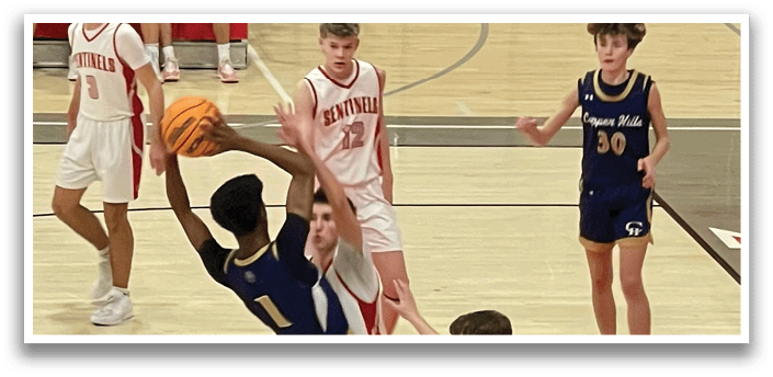 A basketball game is in progress with players on the court. One player is attempting to block a shot, while others are watching the play unfold. The scene includes a total of 11 people, some of whom are sitting on a bench, and others are standing on the court. The players are wearing uniforms, and there is a sports ball visible in the scene. AI generated content