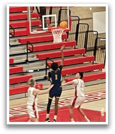 A basketball game is in progress with players on the court. One player is attempting to block a shot, while another player is trying to score. The game is being played in a gym. AI generated content