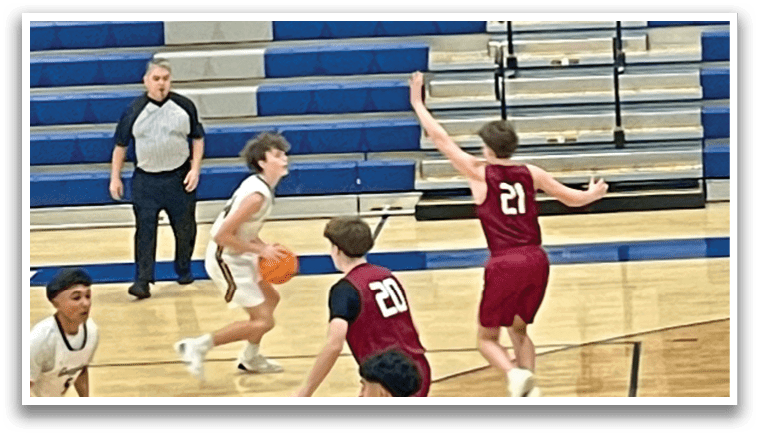 A basketball game is in progress with players on the court. A boy is holding a basketball, and another boy is trying to block him. The referee is watching the play closely. AI generated content