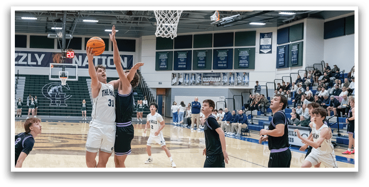 A basketball game is in progress with players on the court. One player is jumping to block a shot, while others are running and trying to get a rebound. The crowd is watching the game intently. AI generated content