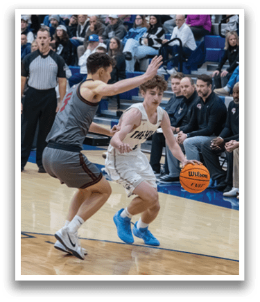 Two men are playing basketball on a court, with one man holding a basketball and the other trying to block him. There are several people watching the game, including some sitting on chairs and others standing. The scene takes place in a gymnasium. AI generated content